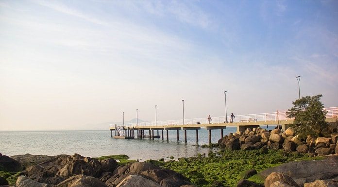 trapiche visto do lado esquerdo da orla em dia de muito sol, mar calmo e maré baixa