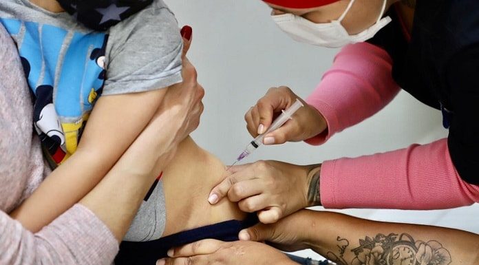 pessoas seguram menina para aplicação de injeção no lado do quadril