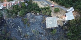 foto aérea mostra topo do morro queimado e casas ao redor