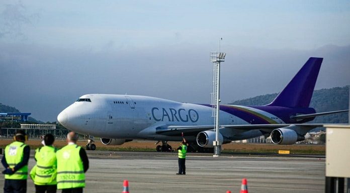 avião com inscrição "cargo" na lateral taxiando no aeroporto hercílio luz com funcionários de pista em primeiro plano