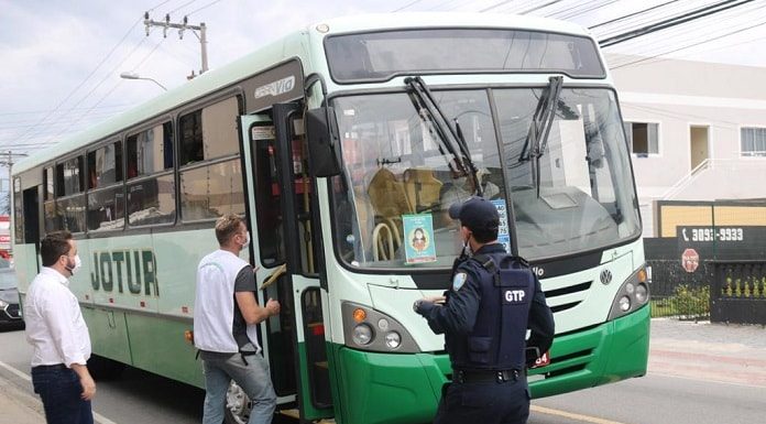 dois ficais e um guarda do município de palhoça em frente a um ônibus da jotur