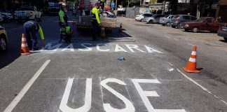 inscrição "máscara use" pintada como sinalização de trânsito no asfalto