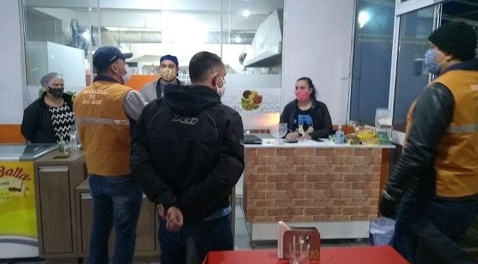 fiscal da vigilância sanitária conversando com dois homens e uma mulher