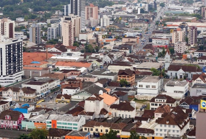 cidade de joinville com centenas de casas e prédios em área plana vista do alto