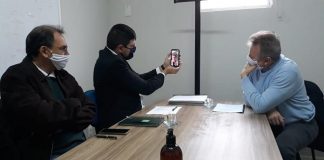 michel schlemper segura celular com transmissão de dario berger; na mesa esta maldaner e mais outro homem