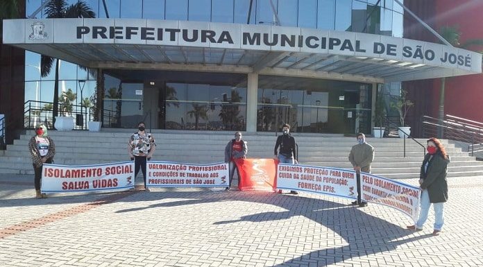 cinco pessoas seguram faixas uma em cada ponta em frente à prefeitura de são josé com mensagens de apoio ao isolamento social