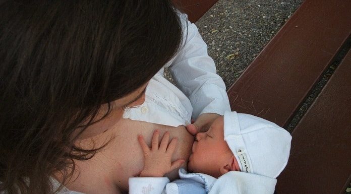 mulher vista de cima dando de mamar a um bebê no seio esquerdo