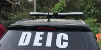 Carro preto com adesivo da DEIC no vidro traseiro