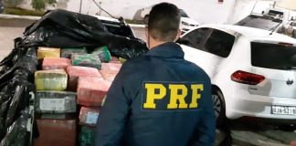 policial da prf de costas em frente à caçamba da saveiro cheia de pacotes embrulhados com plástico