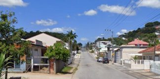 rua de forquilhas ao longo da imagem com diversas residência ao longo. dois carros estacionados