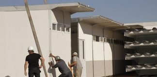 homens montando uma estrutura modular para a escola