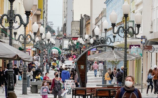 algumas mulheres de máscara andando no calçadão da felipe schimidt no centro de florianópolis; viatura ao fundo