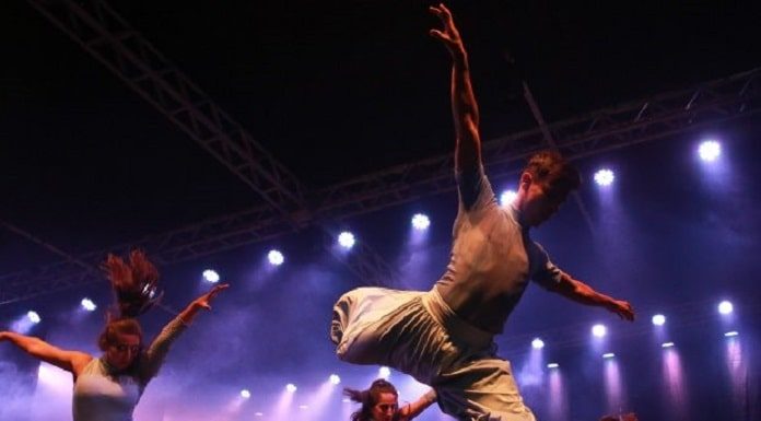 homens e mulheres apresentando uma dança em um palco