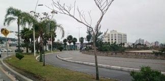 curva do calçadão da beira-mar de são josé junto com ciclovia; não há ninguém; dia nublado; árvores ao longo da orla; prédios ao fundo