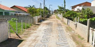 Mulher de 24 anos: imagem da servidão com rua de terra e nome da servidão escrito por cima; casas em volta