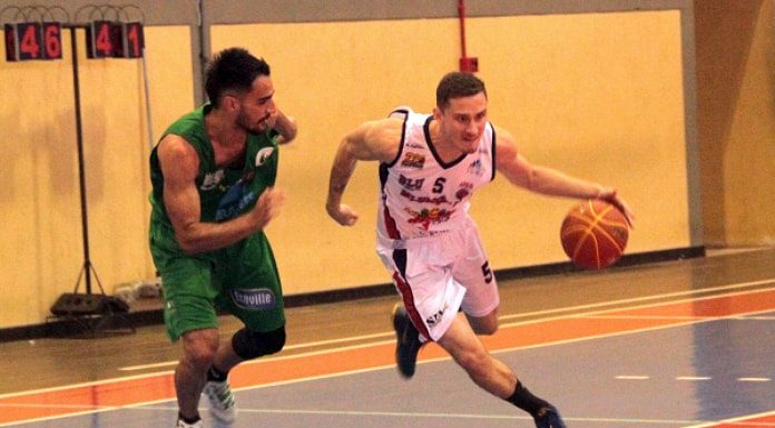 jogador de verde acompanha jogador de branco com a bola de basquete na quadra