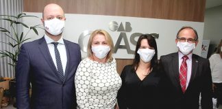 duas mulheres e quatro homens posam para a foto usando máscaras com inscrição da oab caasc em parede ao fundo