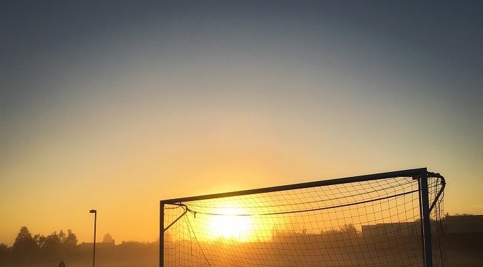 pôr do sol visto no meio de uma trave de futebol com rede