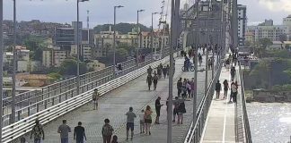 pessoas andando na ponte hercílio luz pelas passarelas e vão central