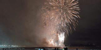 Queima de fogos na praia com pessoas olhando