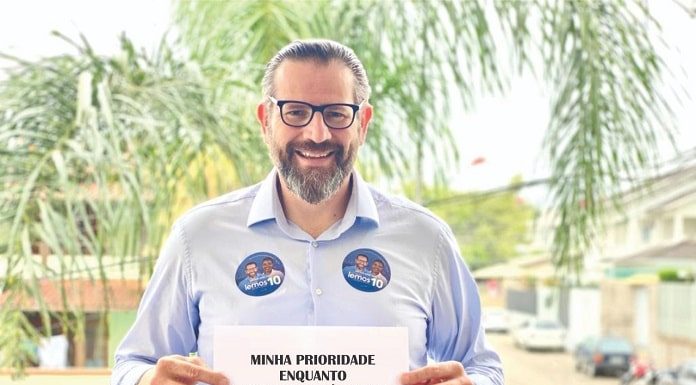 lemos posa sorridente para a foto com uma placa dizendo: Minha prioridade enquanto prefeito será cuidar de nossa gente!