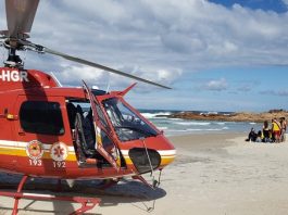 helicoptero arcanjo na frente e ao fundo um grupo atende a vitima de afogamento