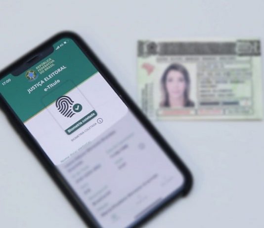 aplicativp e-título em tela de celular com título eleitoral ao lado