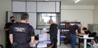 Policiais Civis analisando papeis dentro de uma sala