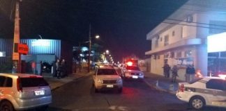 carros de polícia, viaturas e policias em esquina portanto armas próximos à delegacia para onde foram levados os suspeitos de participaram do assalto em criciúma