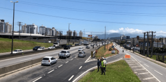 aumentado o acesso da Via Expressa para a BR 101 - faixa nova de asfalto ao lado da rodovia, com homens no canteiro e carros passando