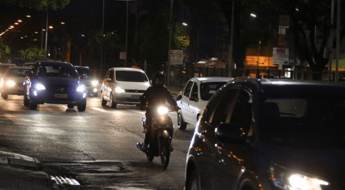 Carros e uma moto de noite nas ruas de Criciúma