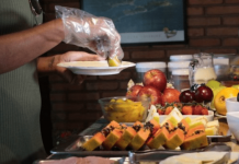 Uma pessoa servindo sua comida com luvas em um hotel