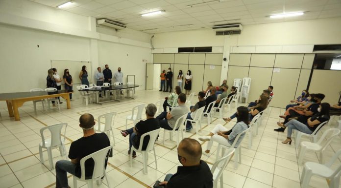 Pessoas sentadas em cadeiras de plástico vendo a posse dos 14 guardas de trânsito em Palhoça