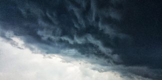 alerta de tempestade no sábado (19/12) para região sul do brasil - nuvem carregada sobre o oceano, com pequena embarcação no horizonte