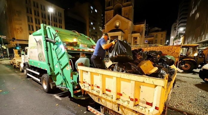 caminhão com caçamba carregada de lixo ao lado de caminhão de lixo estacionado no largo da matriz