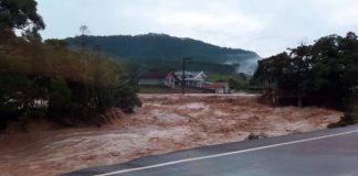 mortos em enxurrada no alto vale do itajaí: rio transbordado com forte enxurrada ao lado de estrada