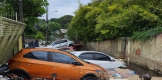 Lagoa artificial rompe - foto mostra carros empilhados em servidão alagada com espuma e diversos objetos boiando