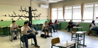 calendário escolar estadual - alunos sentados em carteiras separadas usando máscara dentro de sala de aula