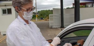 plano de vacinação de coronavírus em são josé preve drive-thru; mulher da vacina em braço de motorista dentro de carro