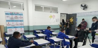 alguns alunos usando máscaras em carteiras com outros adultos de máscara na sala - aulas em são josé retornam em 22 de fevereiro