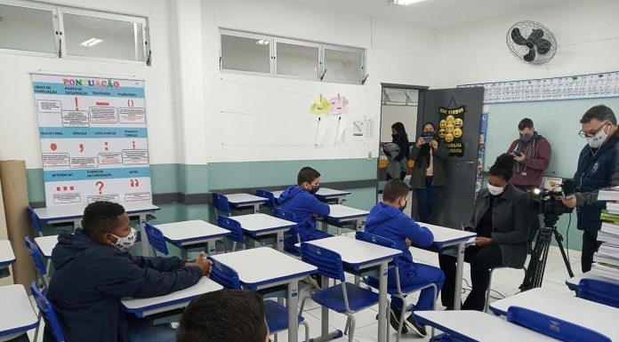 alguns alunos usando máscaras em carteiras com outros adultos de máscara na sala - aulas em são josé retornam em 22 de fevereiro