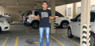 Vereador Cryslan do partido NOVO, parado no meio da garagem com os braços abertos