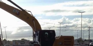 retroescavadeira e operário em rua ao lado da obra de manutenção da adutora da casan