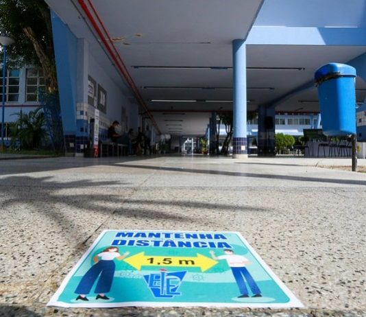 cartaz colado no chão informa sobre necessidade de alunos manterem distanciamento nas escolas para o retorno às aulas; chão do IEE