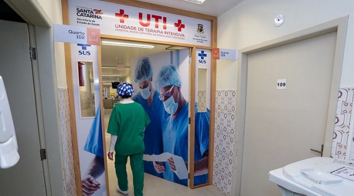 profissional de saúde com trajes entra em porta da ala de uti do hospital de nova trento