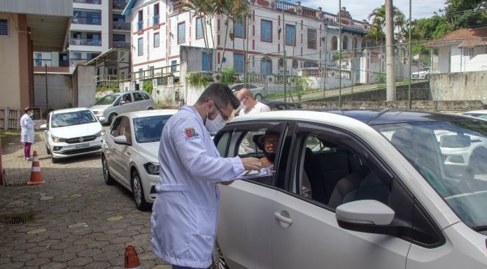 profissional de saúde ao lado de carro em fila de drive no dia em que são josé vacinou 25% dos idosos com mais de 85 anos