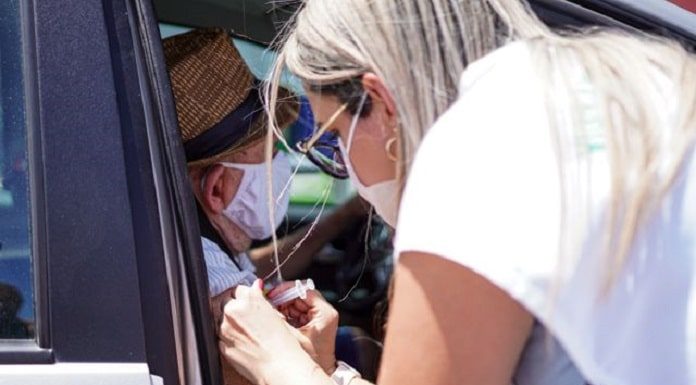 profissional de saúde aplica vacina no braço de idoso dentro de carro - Vacinação contra Covid em idosos a partir de 78 anos tem início em Palhoça