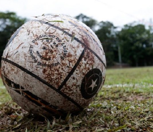 Uma bola branca suja de barro e ao fundo um campo de grama. A foto ilustra a alteração do governo no decreto de medidas restritivas, agora os esportes recreativos estão autorizados em SC.