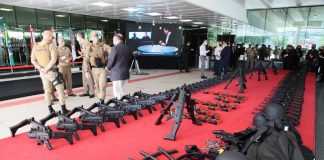 No tapete vermelho da Alesc os armamaentos estão distribuídos lado a lado. Ao fundo da foto pessoas reunidas e mais a frente um grupo de policiais militares fardados. A Polícia Militar de SC recebeu hoje viaturas e equipamentos em ato simbólico na assembleia.