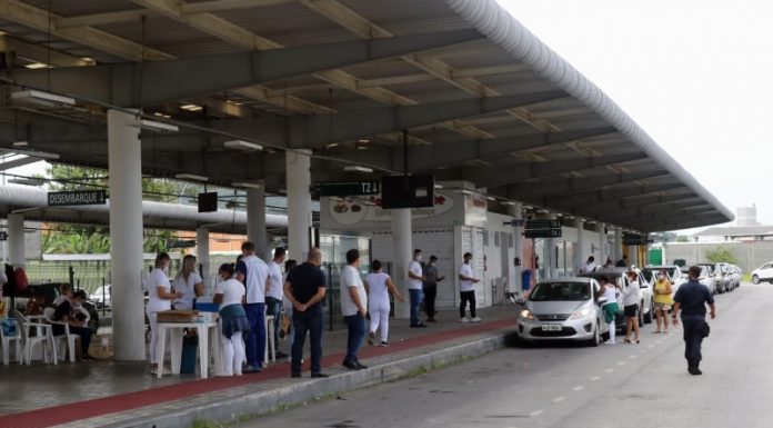 estação palhoça, onde é feita a vacinação por drive-thru; profissionais de saúde na plataforma; fila de carros; policial na pista